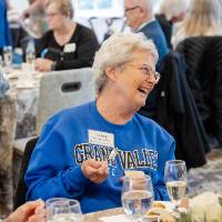 Event guest sitting at table, smiling at person sitting next to her
